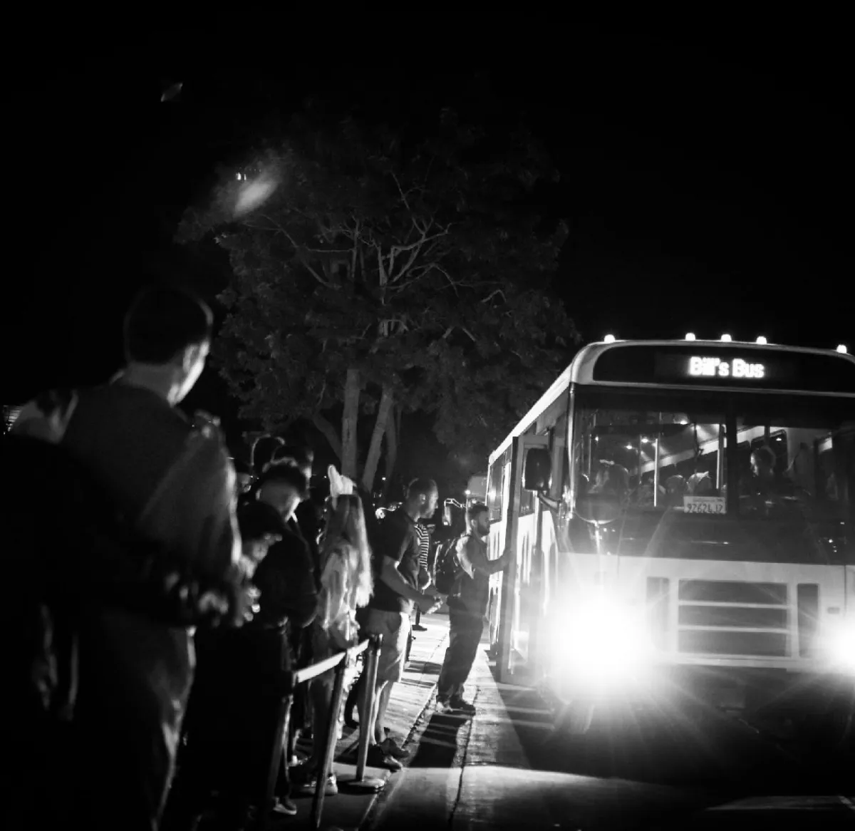 A group of people sitting on a bus, each holding drinks and engaged in conversation.
